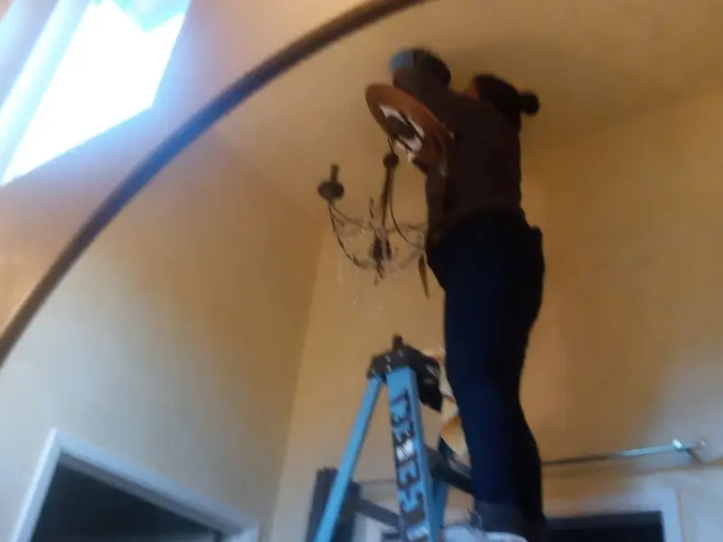 Electrician installing a chandelier in a Diboll residence